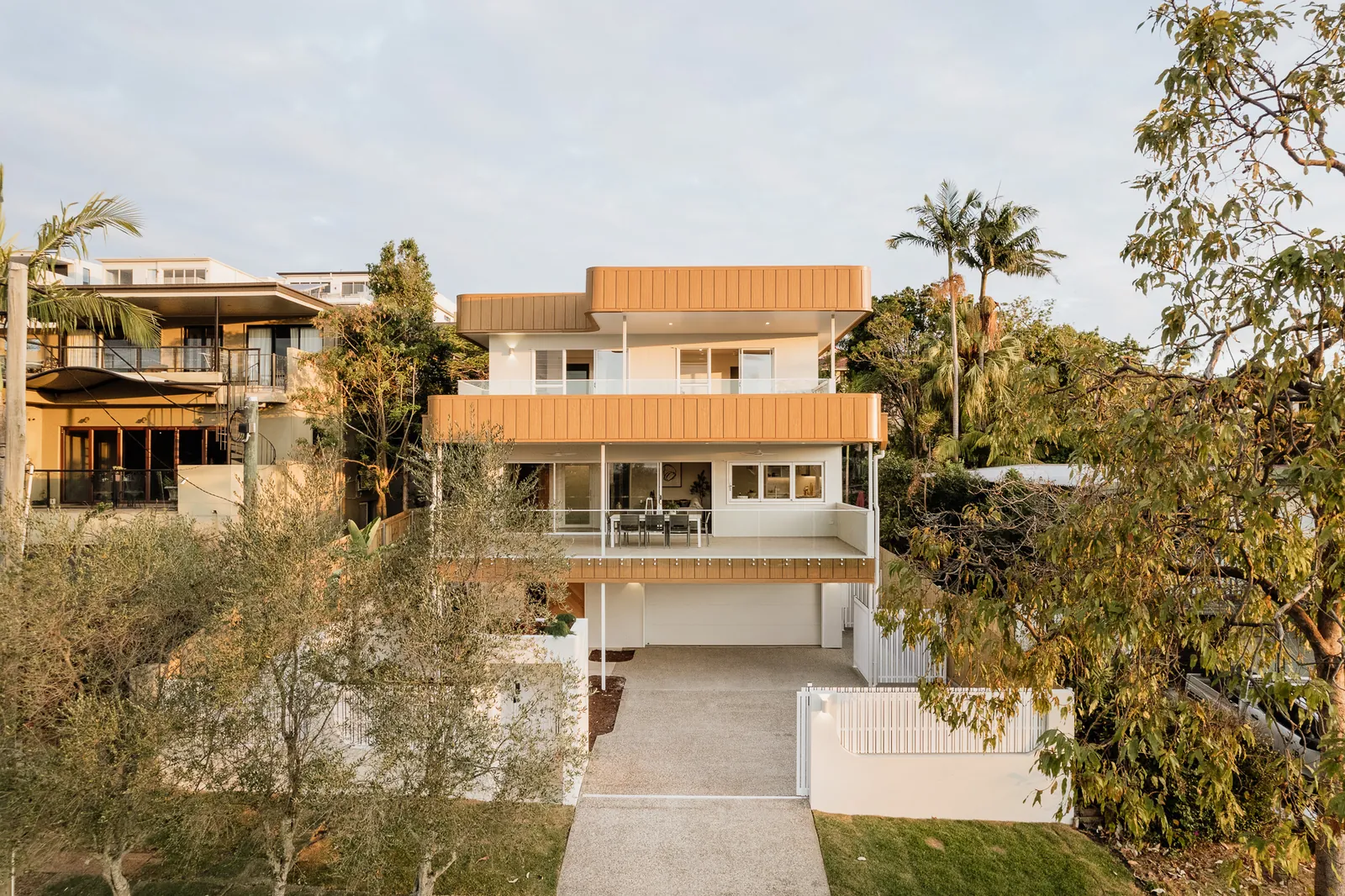 The completed three-level Holland Park home on its hillside site, with timber-lined soffits, glazed balustrades and established palms