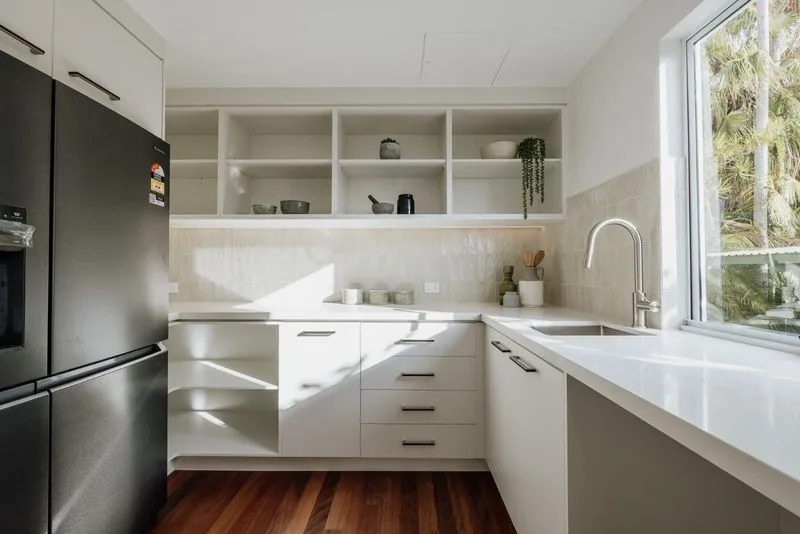Kitchen with white cabinetry, open shelving, integrated fridge and stone benchtops