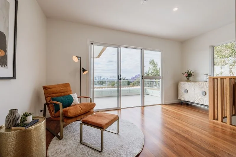Sitting area with a leather armchair and ottoman, hardwood floors and sliding doors to the terrace