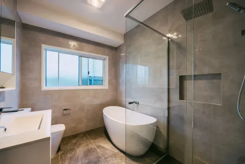 Bathroom with a freestanding bath, walk-in shower and full-height grey tiling