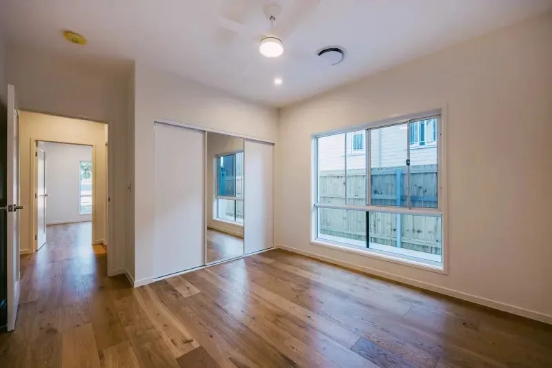 Bedroom with engineered timber floors, built-in robes and a window to the side garden