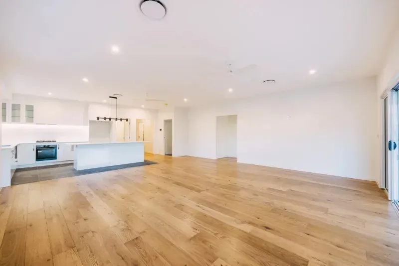 Living area looking through to the kitchen, with a raked ceiling and timber floors