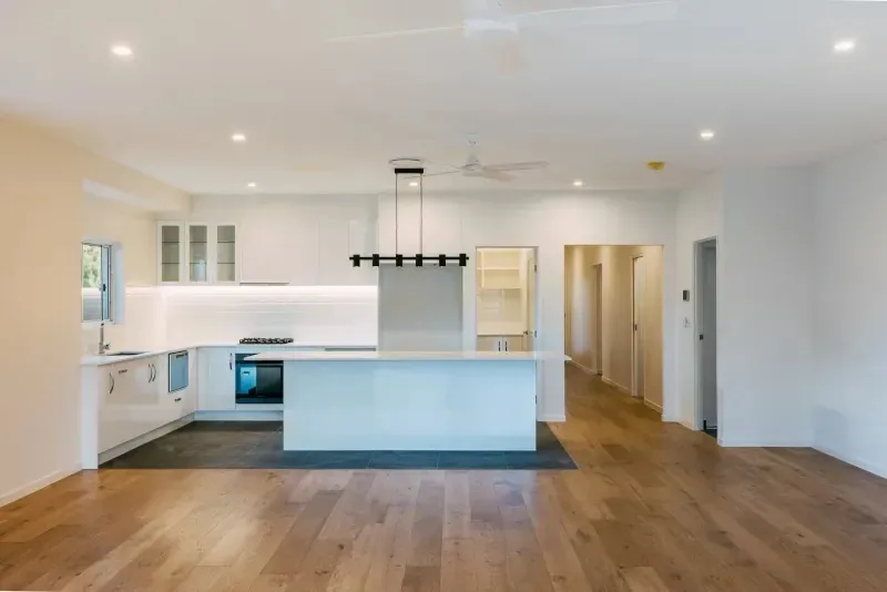 Kitchen and living space with island bench, pendant lighting and engineered timber floors