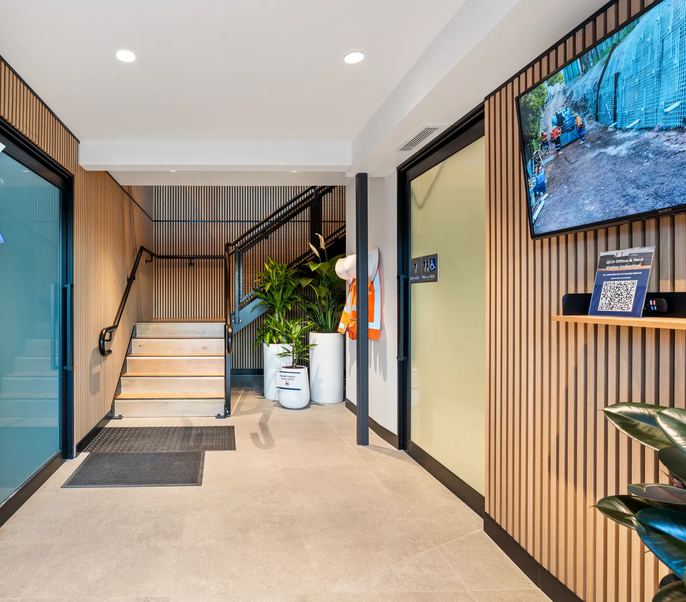 Entry lobby with timber batten walls, a stair to the upper level and planting at the base