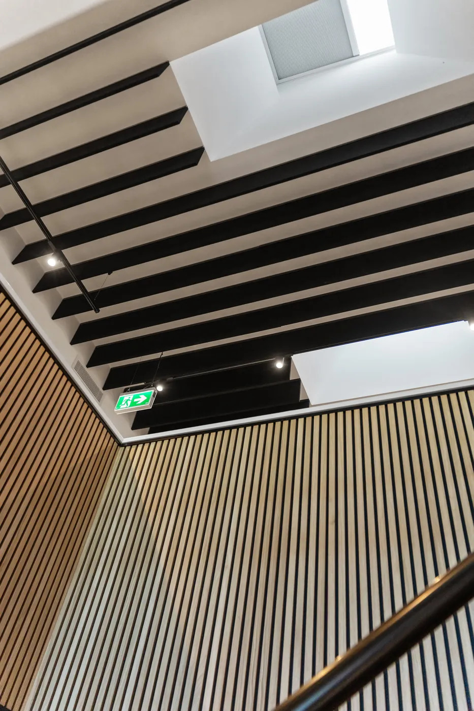 View up the Sumner fit-out stairwell to exposed black ceiling beams, skylights and timber batten walls