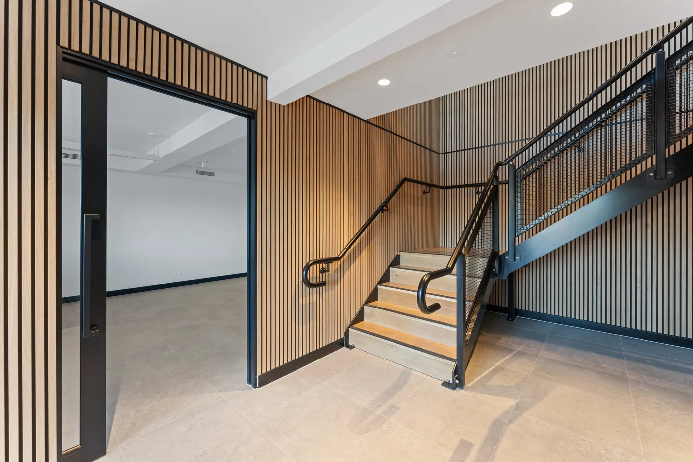 Entry stairwell at the Sumner fit-out with timber batten walls, a black steel balustrade and timber treads