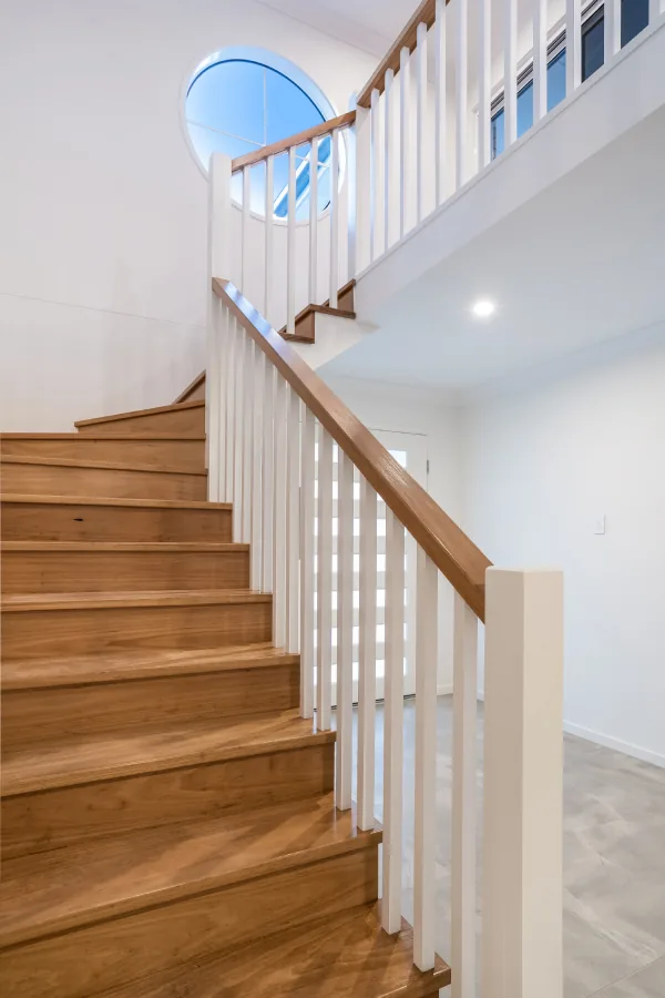 Hardwood staircase with a white painted balustrade rising to the upper level