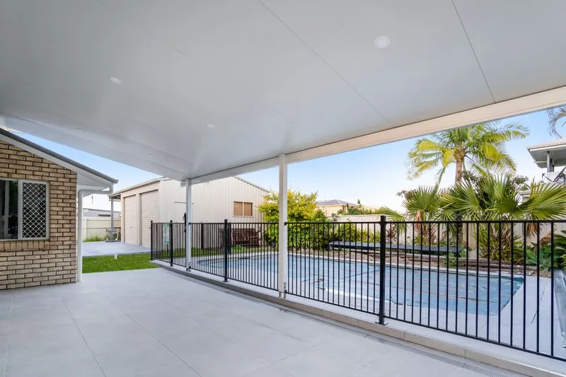 Covered patio with a black balustrade looking over the pool and garden